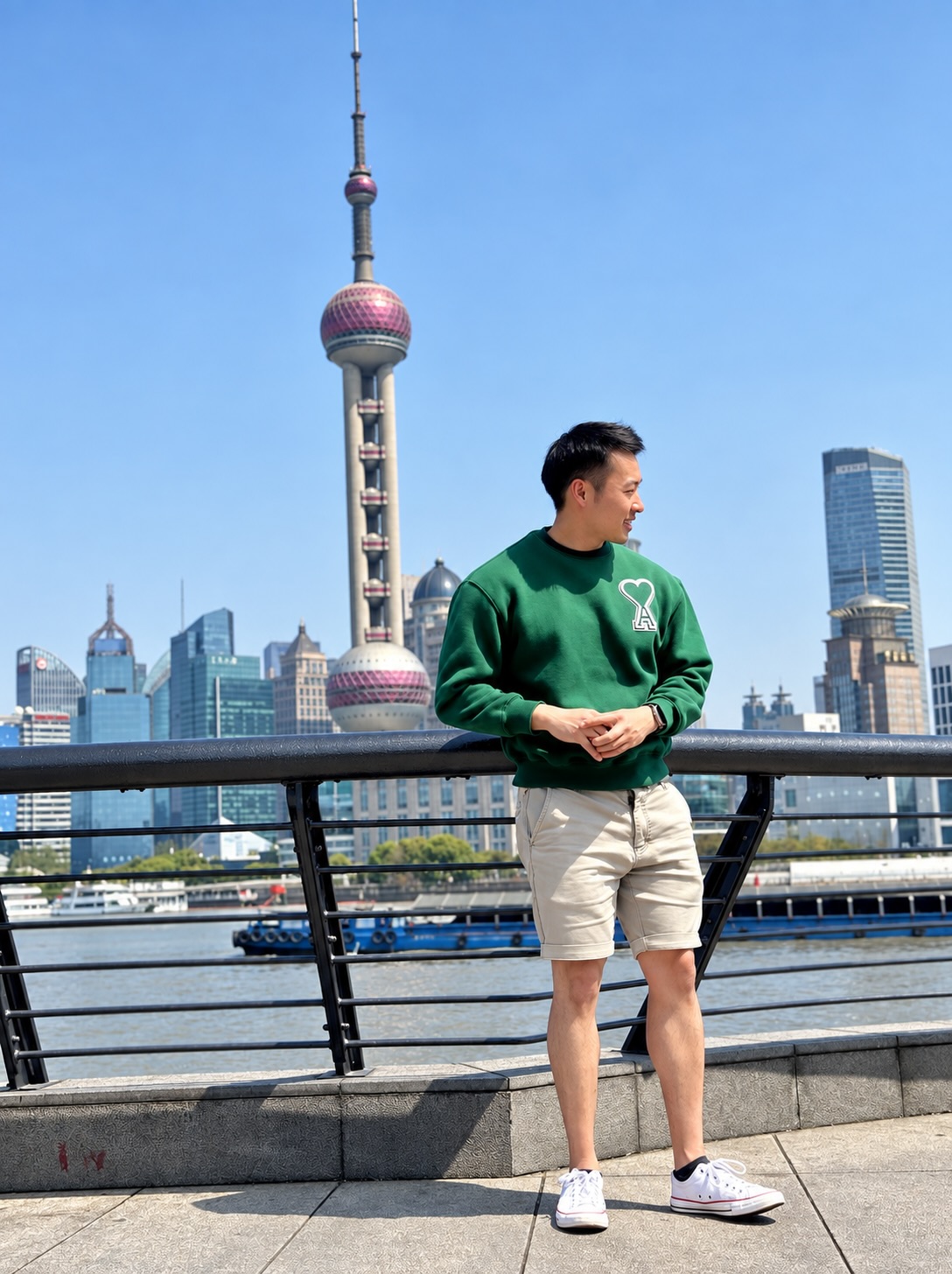 Andy in a green sweatshirt beside the Huangpu River, with Shanghai’s Oriental Pearl Tower behind him