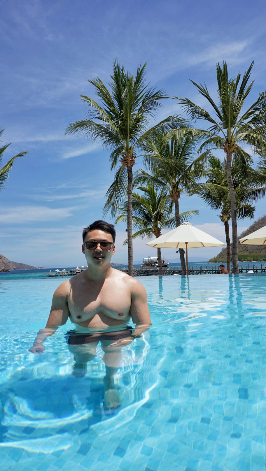 Andy in a tropical pool beneath palm trees